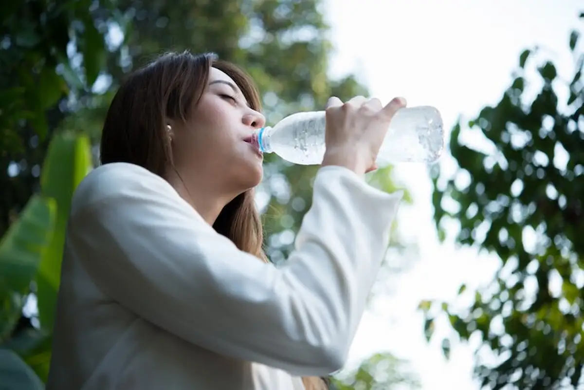 seorang wanita meminum air kemasan