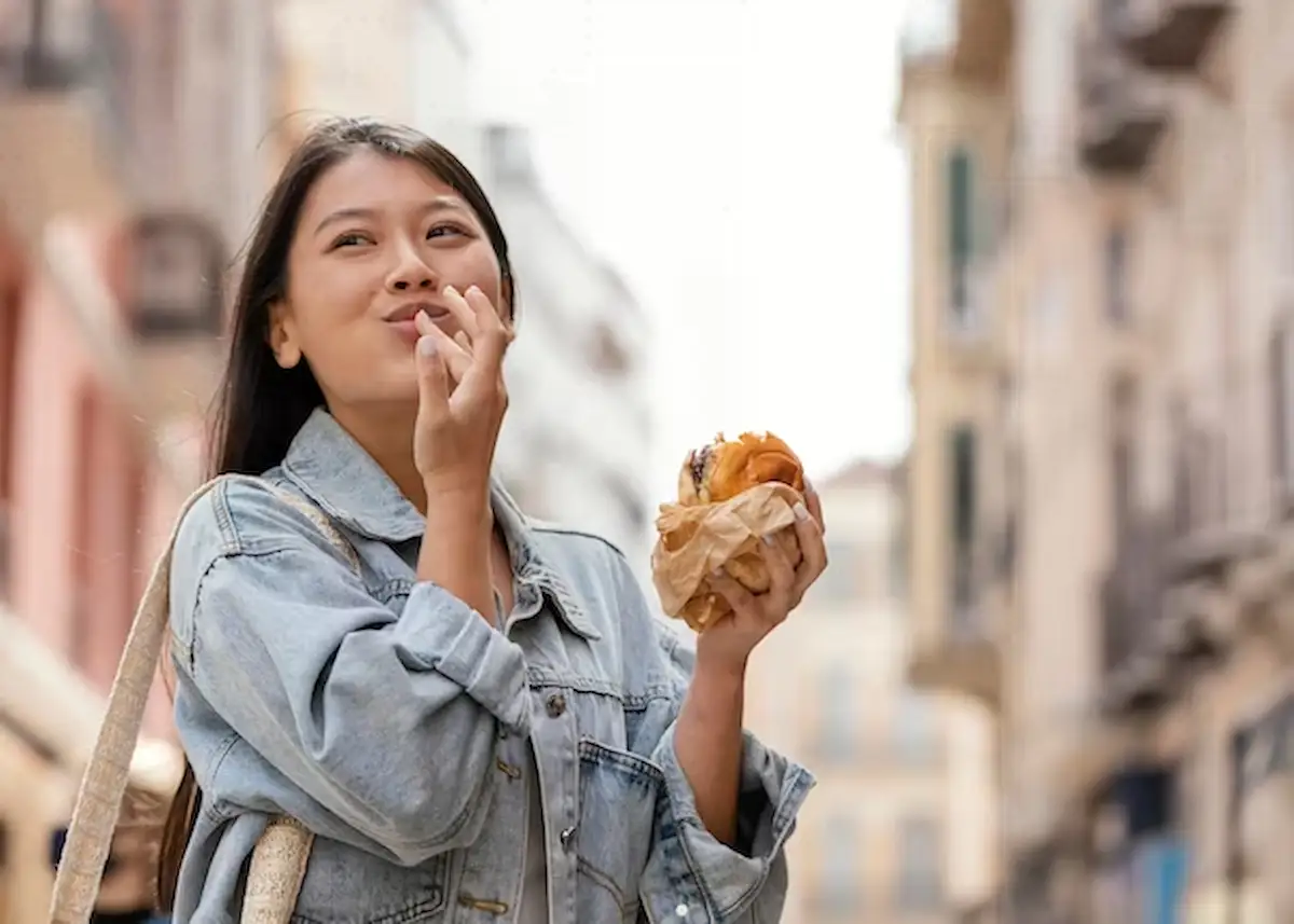 seorang wanita sedang makan di jalan