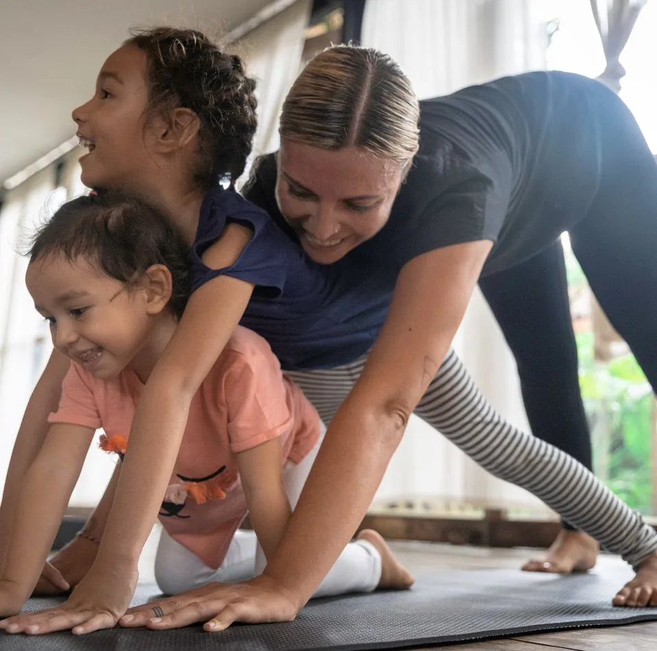 An adult with two of her kids doing fun yoga together - Bali map for kids