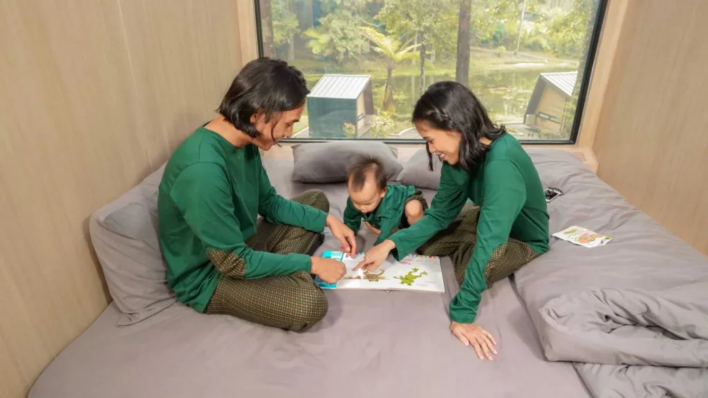 A family of three inside Bobocabin with the kid drawing on a piece of paper