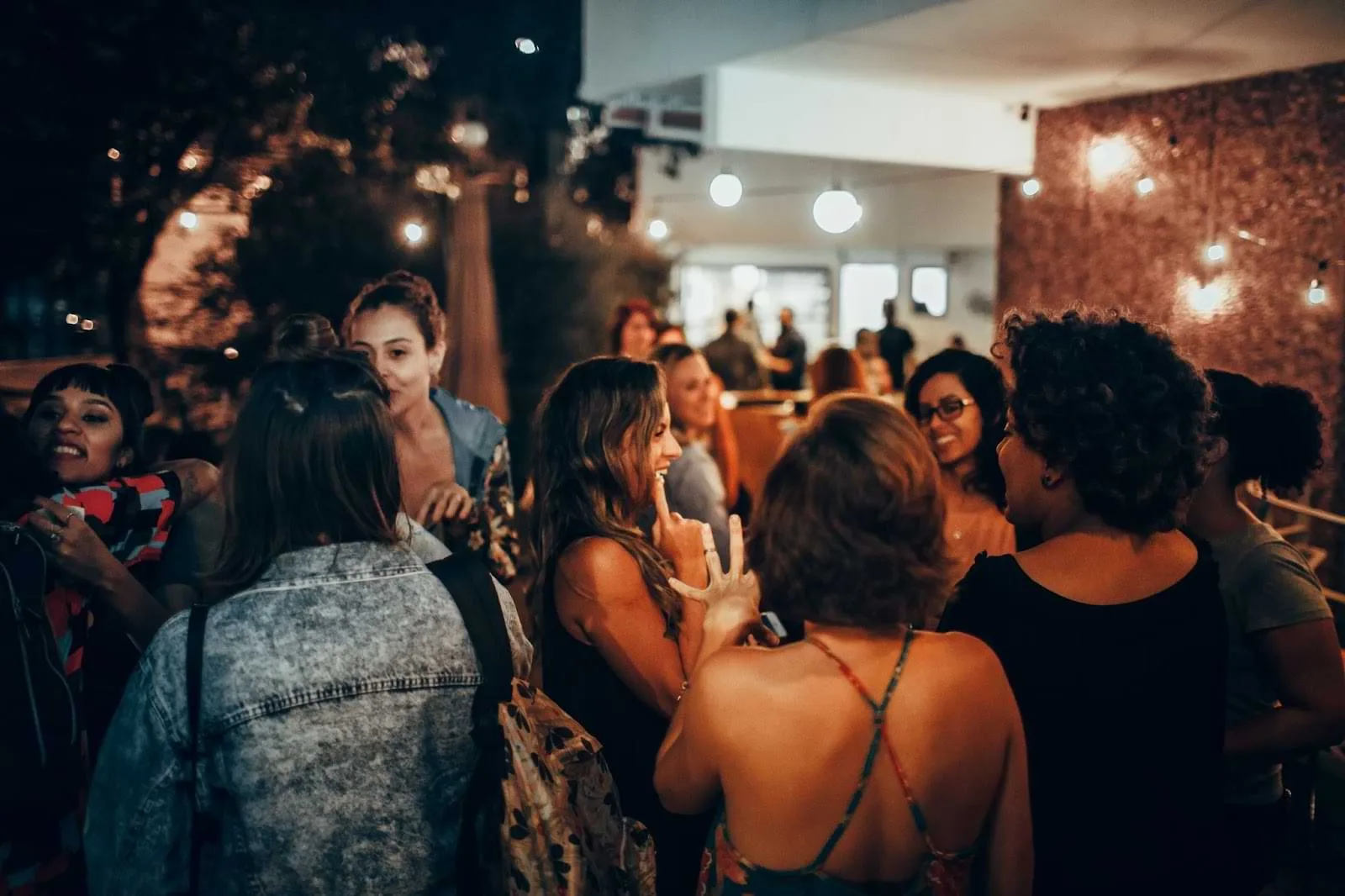 A group of women engaging in conversation at an evening social gathering outdoors