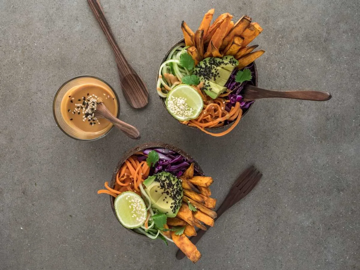 Two bowls of mixed vegetables and fries with dipping sauce and wooden utensils - best restaurants in Seminyak