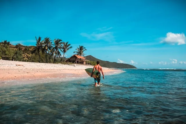 A man on a beach with white sand and blue sea - best time to visit lombok