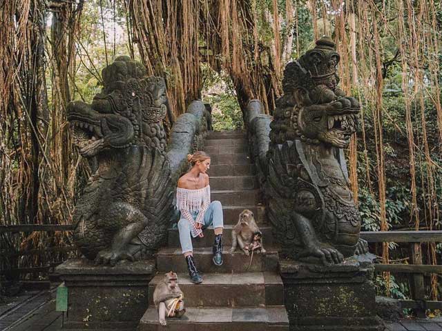 A woman posing in Ubud Monkey Forest with two long-tailed monkeys - Ubud itinerary