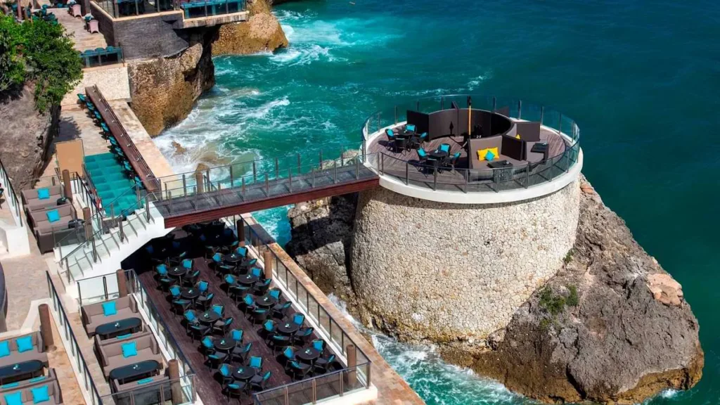 An aerial view of an oceanfront dining area set on a circular cliffside platform - best bars bali