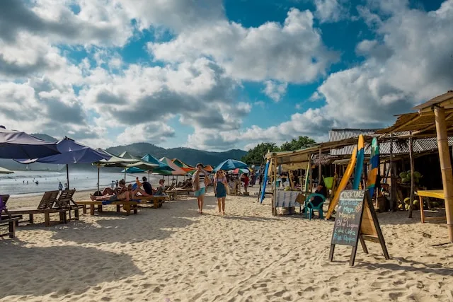 People, vendor stalls, and lounging chairs at a beach in Lombok - best time to visit lombok