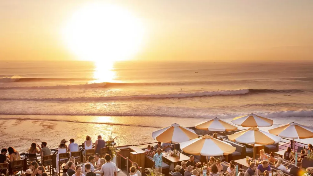 Sunset view at Single Fin Bali with people enjoying the seaside ambience under umbrellas