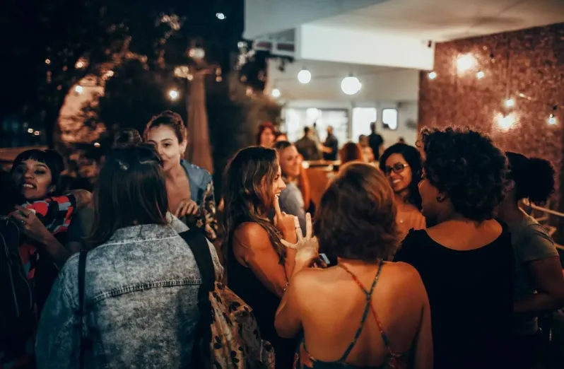 A group of women engaging in conversation at an evening social gathering outdoors