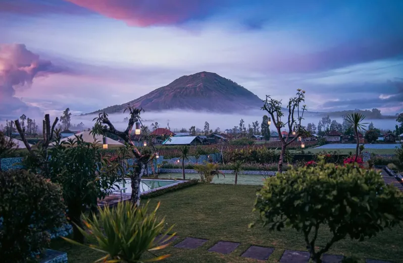 A view of Mount Agung surrounded by early, purple morning mist
