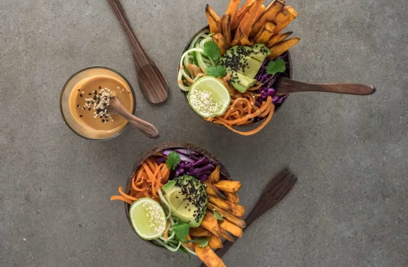 Two bowls of mixed vegetables and fries with dipping sauce and wooden utensils - best restaurants in Seminyak